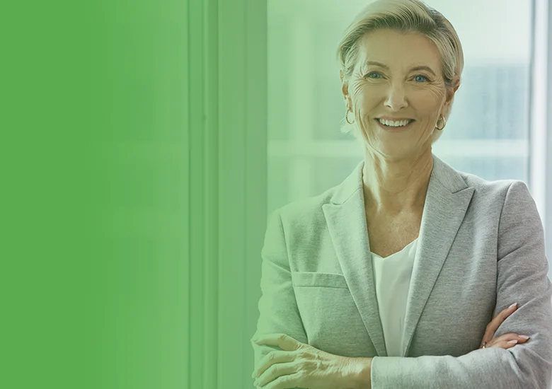 Business Coaching Köln & Personal Coaching - Frau Führungskraft steht vor einem Fenster im Anzug und lächelt - Alexander Klein